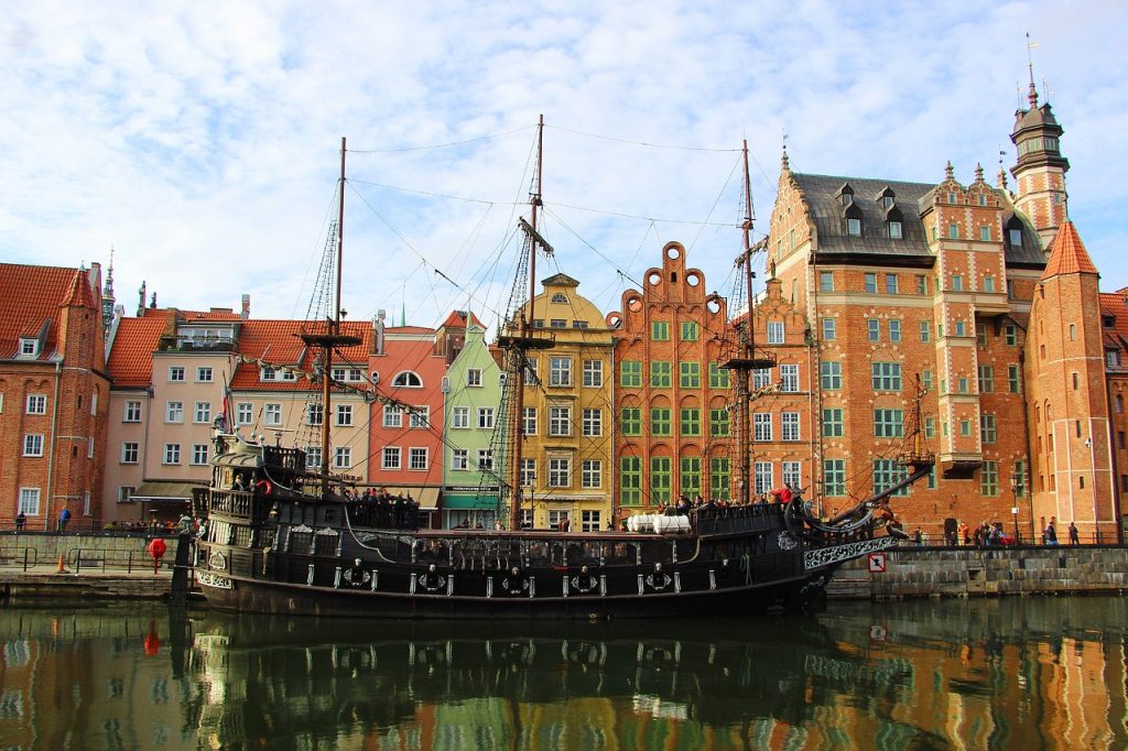 Bateau ancien amarré sur la rivière Motława à Gdańsk devant les façades colorées du vieux port