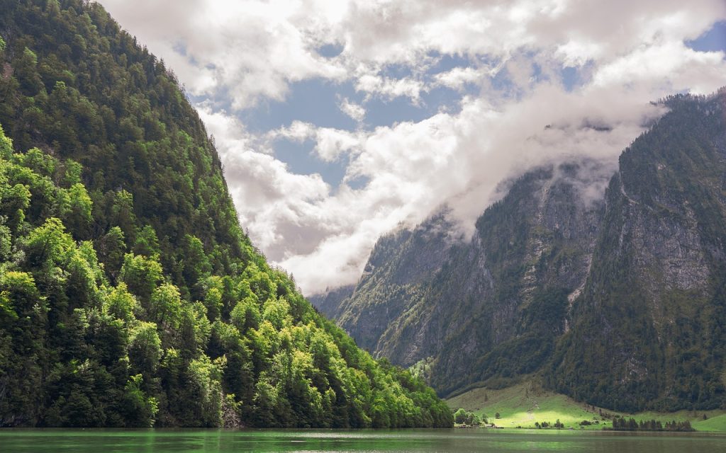 Paysage du lac Königssee entouré de montagnes vertes et brumeuses dans les Alpes bavaroises.