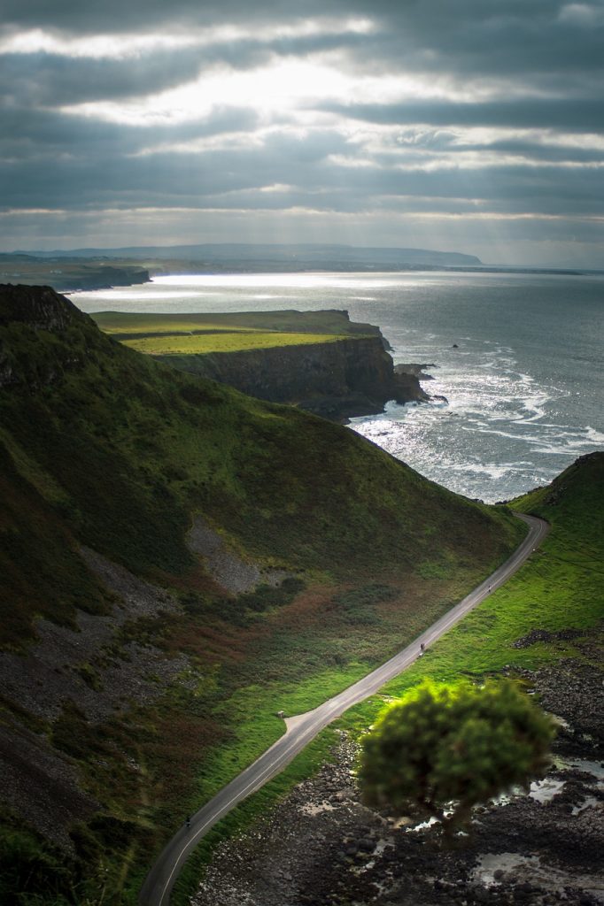 Route sinueuse longeant les falaises de la Causeway Coast en Irlande du Nord, vue sur l’océan.